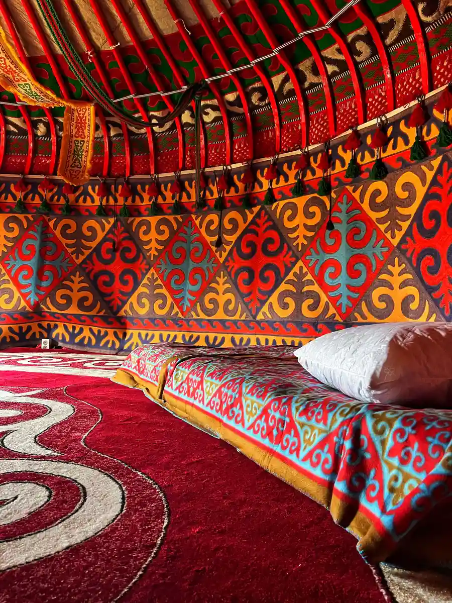 Sleeping area inside a traditional yurt with colorful patterned blankets and pillows